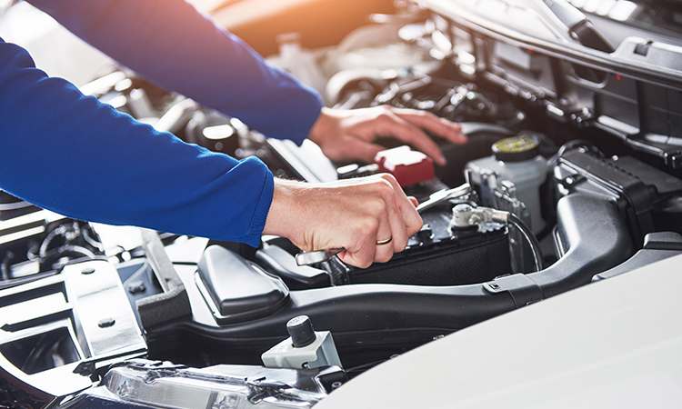 Hands of car mechanic with wrench in garage